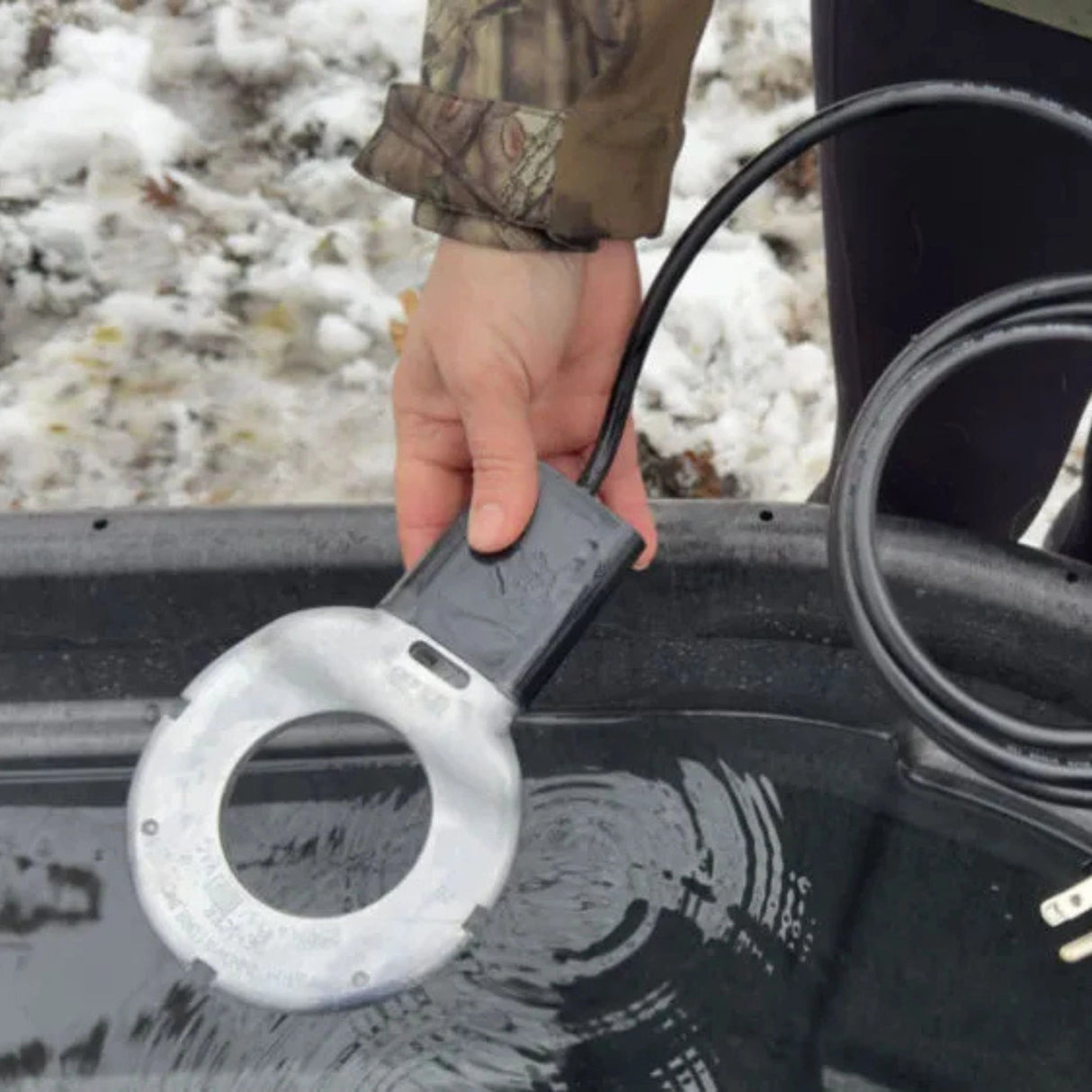A person setting up the Farm Innovators 250W Aluminum Utility Bird Bath Deicer outdoors during winter in Kamloops, British Columbia
