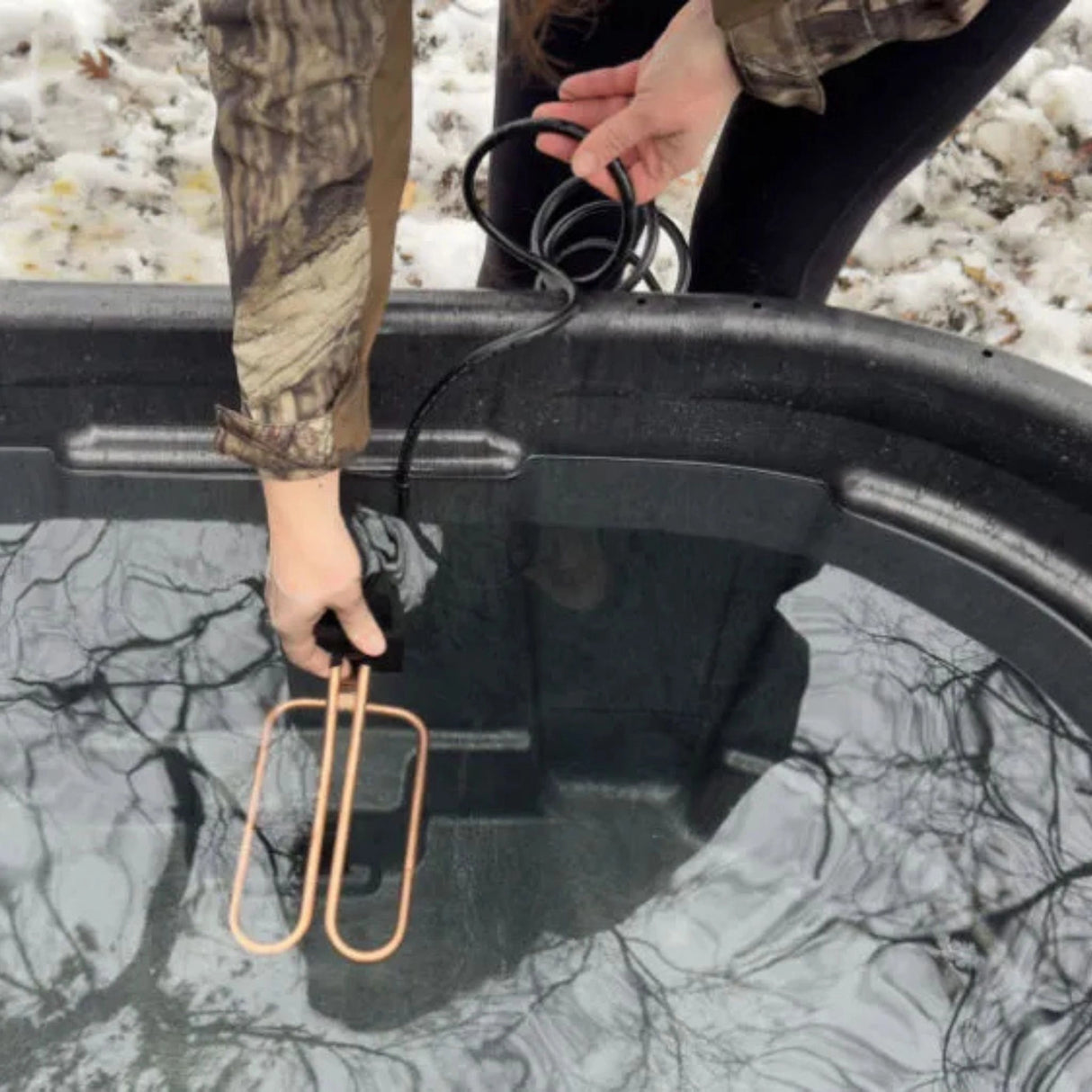A person using the 1500W Universal Drain Plug De-Icer by Farm Innovators in the outdoors of Kamloops, British Columbia