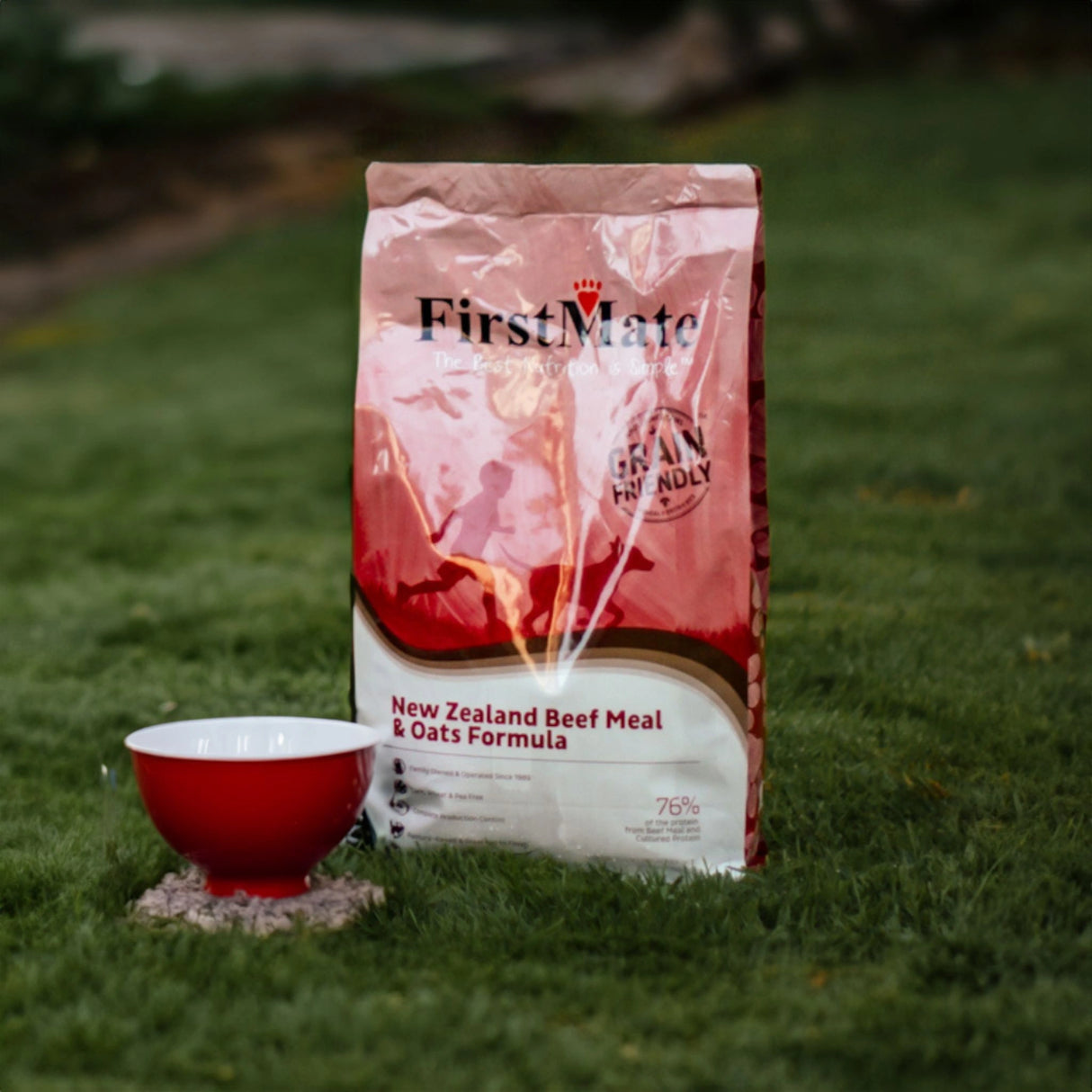 A bag of First Mate New Zealand Beef and Oat dog food bag on the grass with a red bowl outside, Kamloops, British Columbia