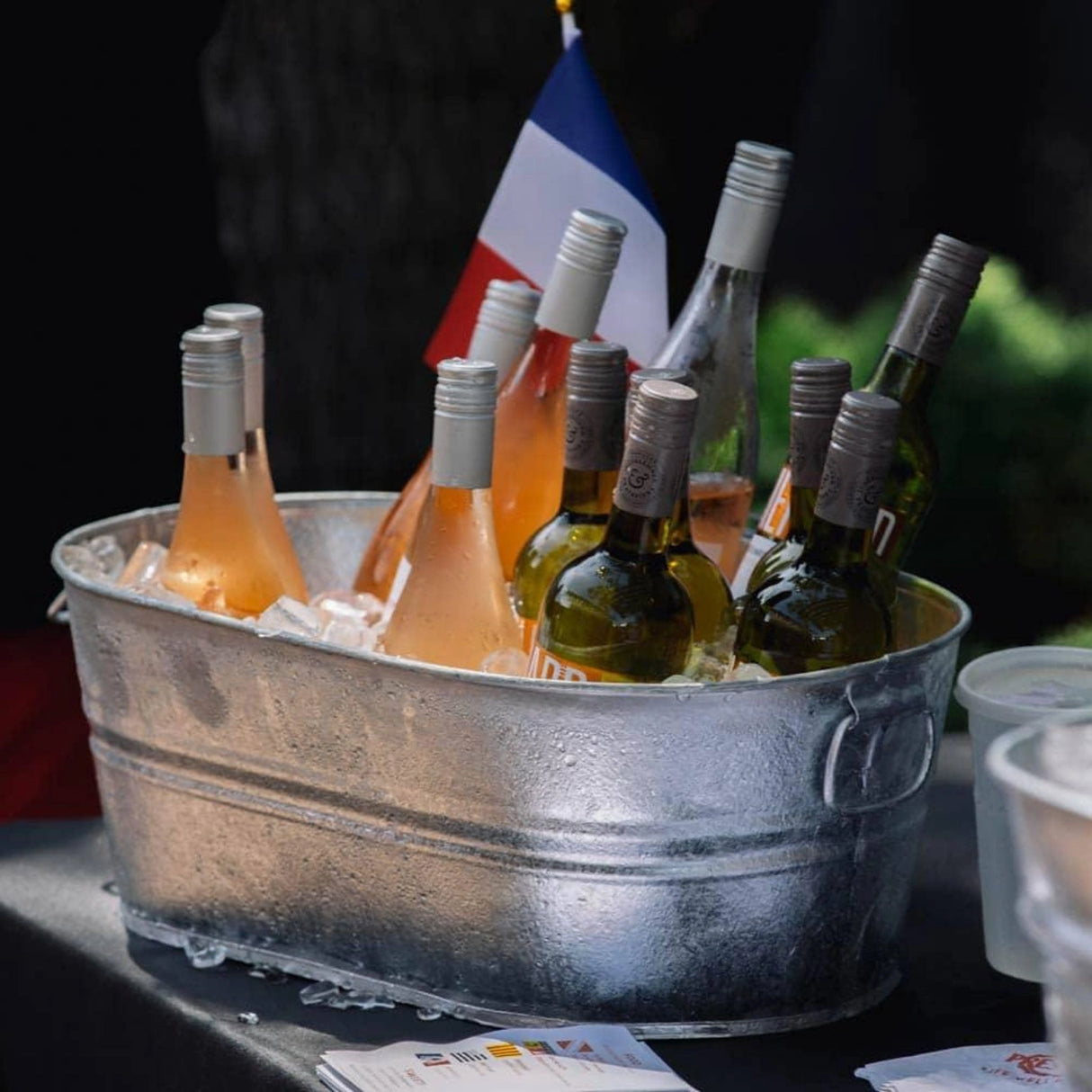 A galvanized 5.5 Gallon Hot Dipped Steel Oval Tub filled with ice and beverages, placed outdoors in Kamloops, British Columbia