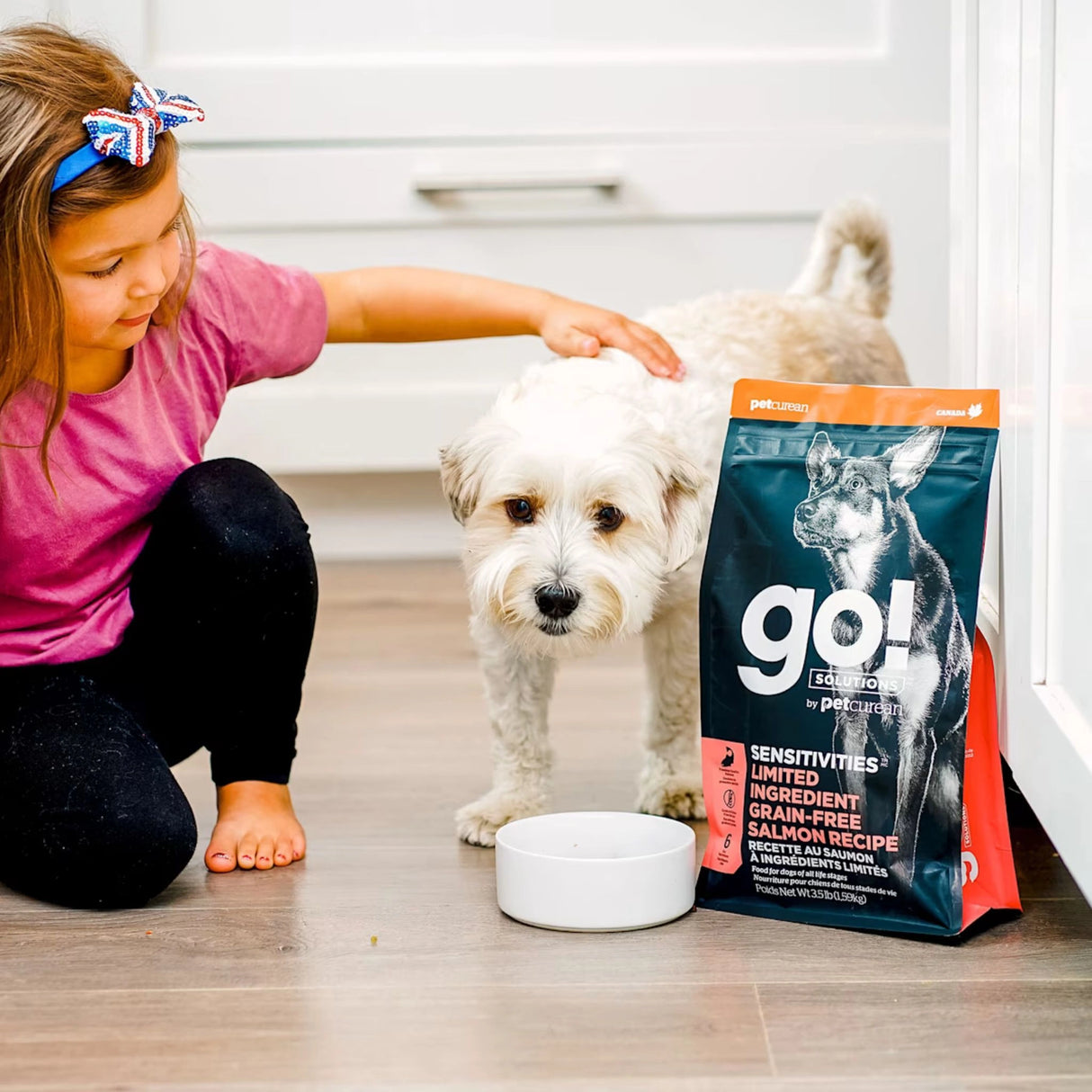 A little girl petting a happy dog enjoying Go! Solutions Sensitivities Limited Ingredient Grain Free Salmon Recipe Dog Food in Kamloops, British Columbia