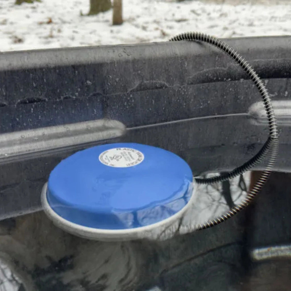 A 1250W Farm Innovators Pond De-Icer floating in a tub outdoors in Kamloops, British Columbia
