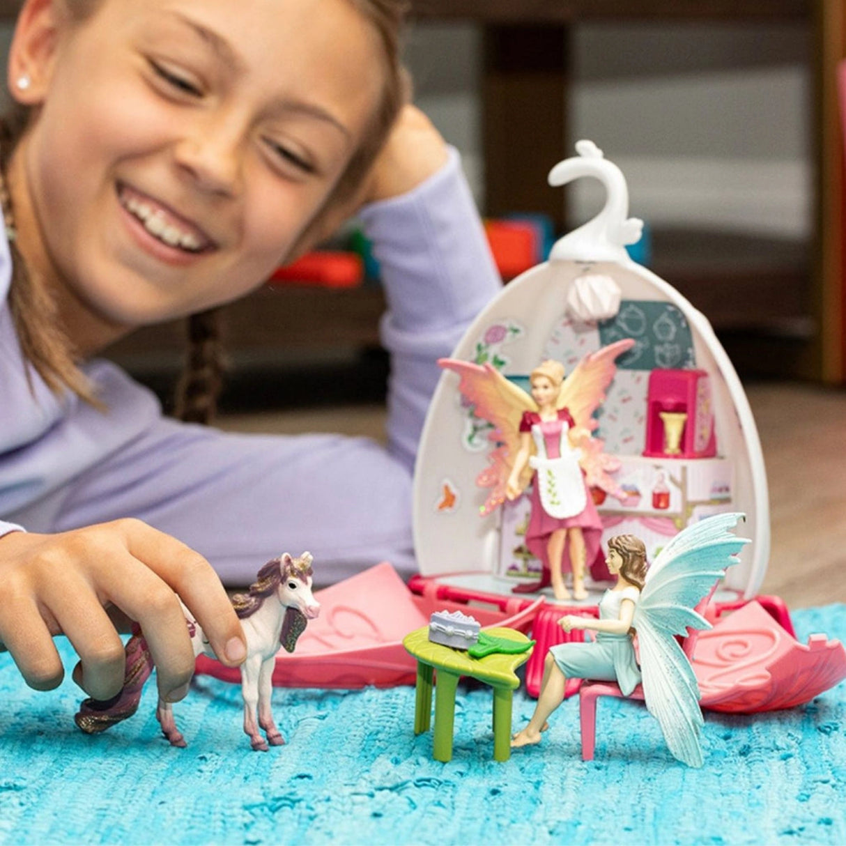 A child playing with the Schleich Fairy Café Blossom fairy toy set in a cozy playroom