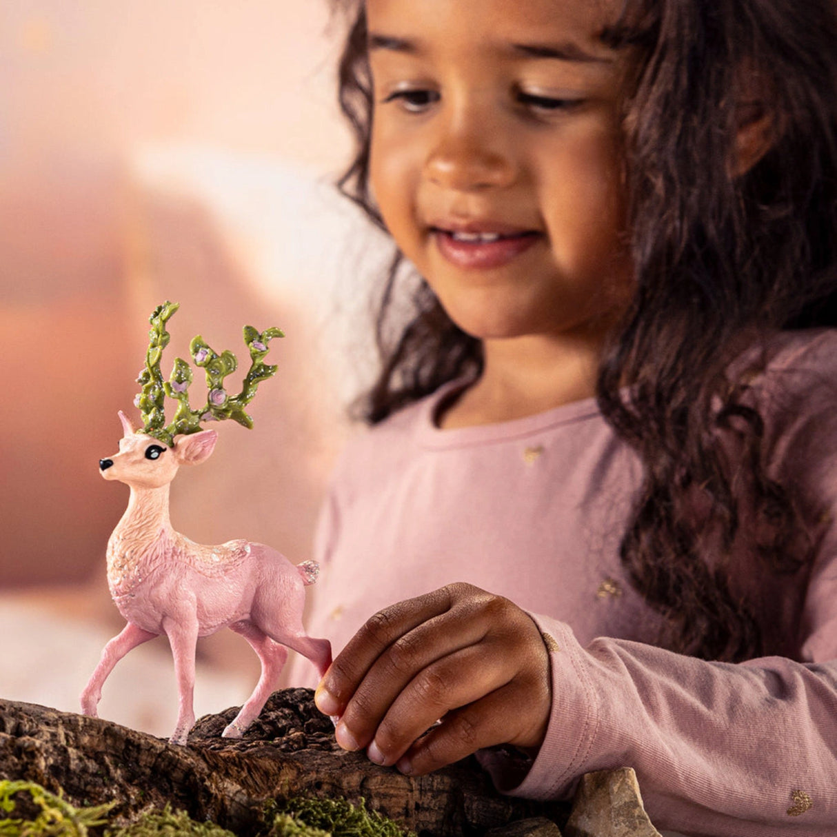 A young child creating a fantasy scene with the Schleich Bayala Magic Deer toy in a playroom