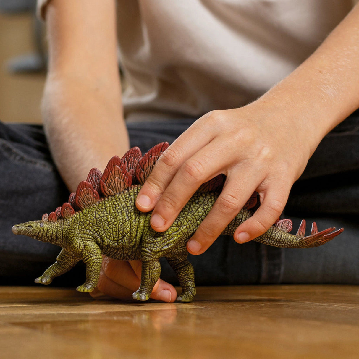 Young child engaging with a Schleich Dinosaurs Stegosaurus figure during imaginative play indoors