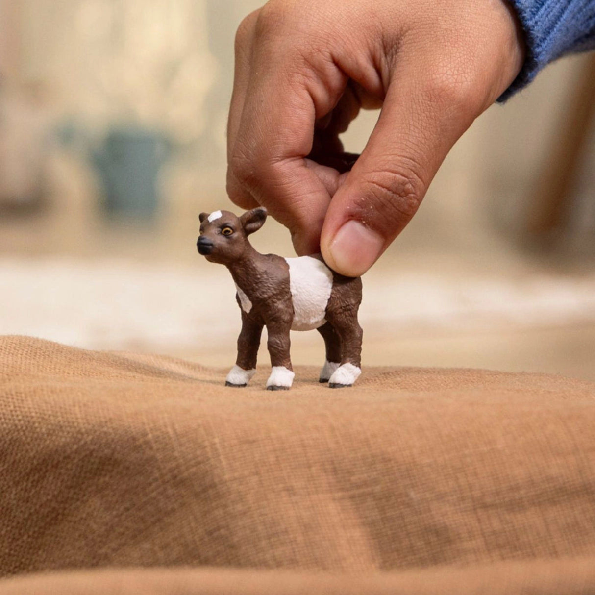 child playing with Schleich Farm Animal Toy Goat Kid inside a playroom