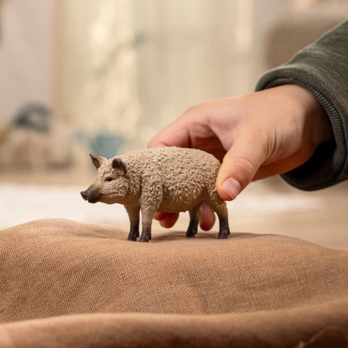 A child playing with a Schleich Mangalica Pig farm animal toy