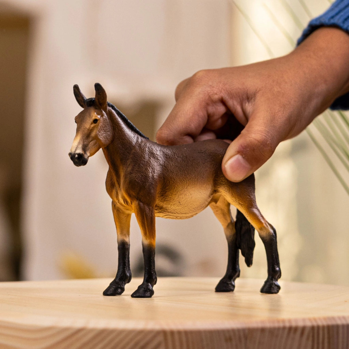 Schleich mule farm animal toy being played with by a child in a playroom