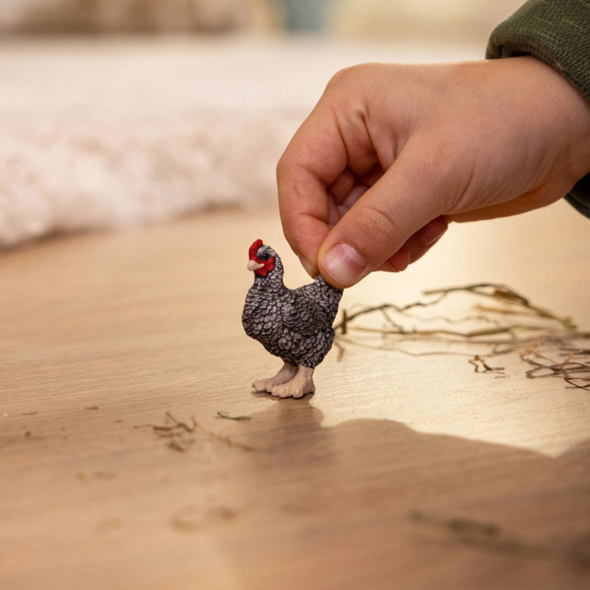 A child playing with Schleich Plymouth Rock Chicken farm animal toy inside a playroom