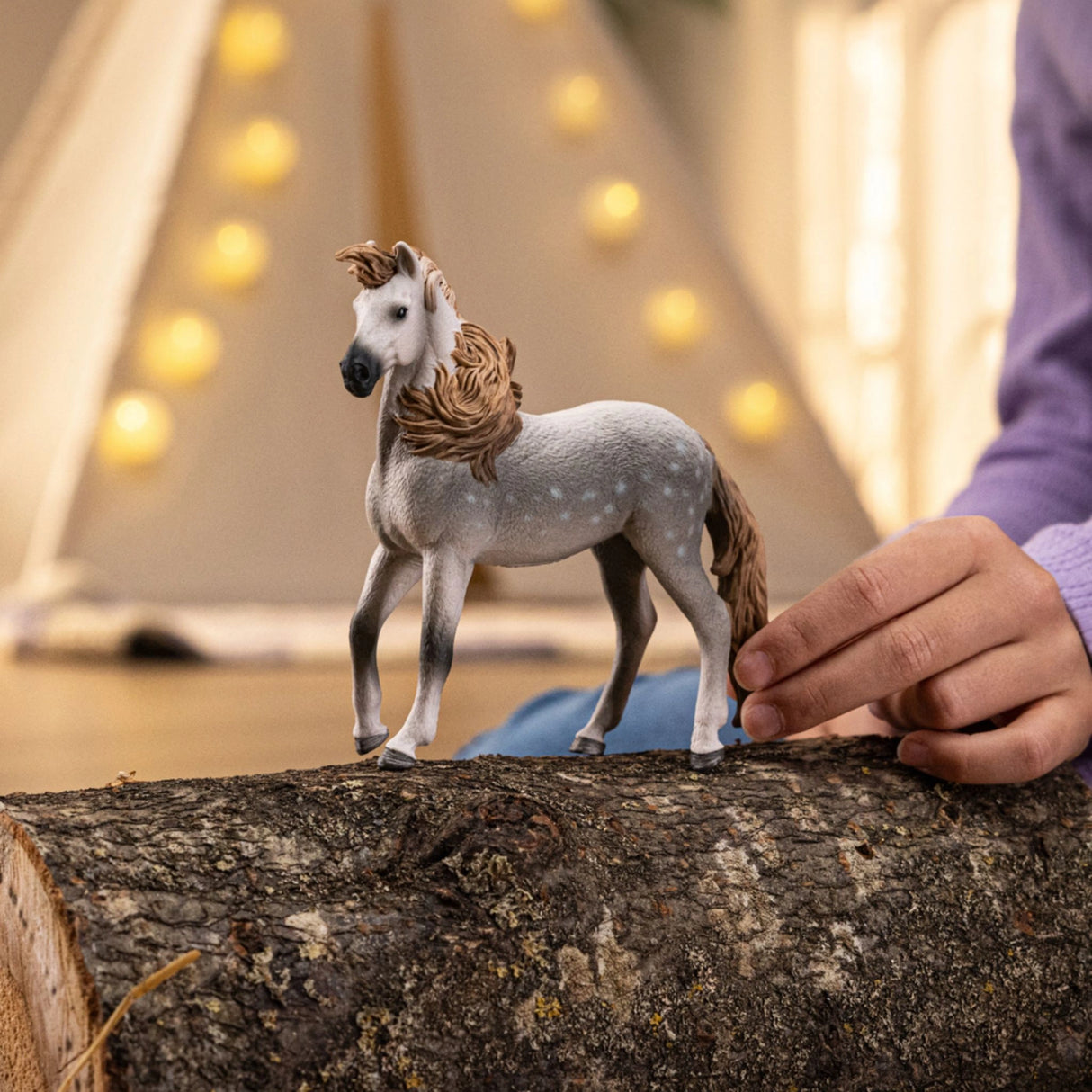A child playing with the Schleich Andalusian Stallion horse toy in a colorful playroom