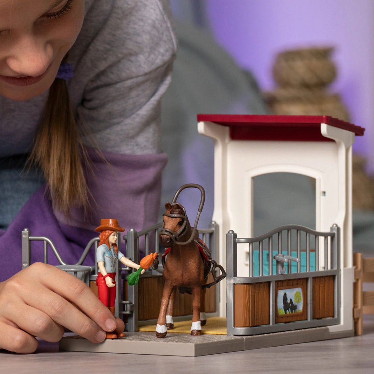 A child engaging in imaginative play with Schleich animals Horse Box and figures in a cozy playroom