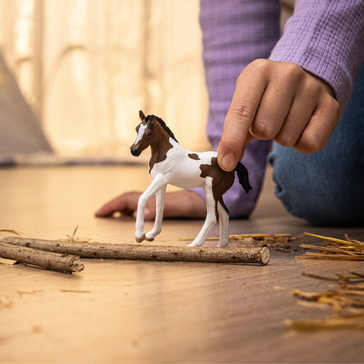 A child playing with the Schleich Horse Toy Paint Horse Foal inside a playroom