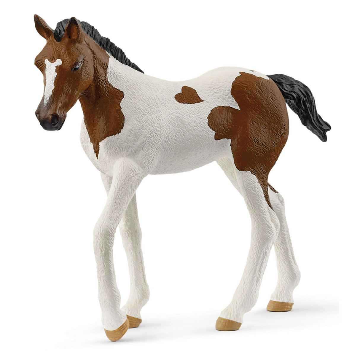 A close-up view of Schleich animals Paint Horse Foal figurine on a white background