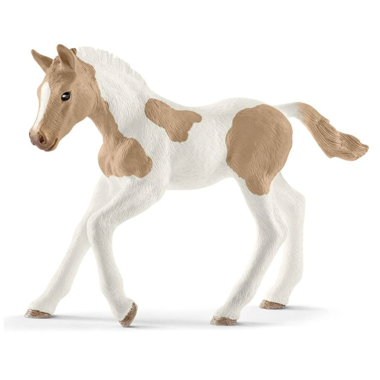 A close-up view of Schleich Paint Horse Foal toy with light brown patches on a white background