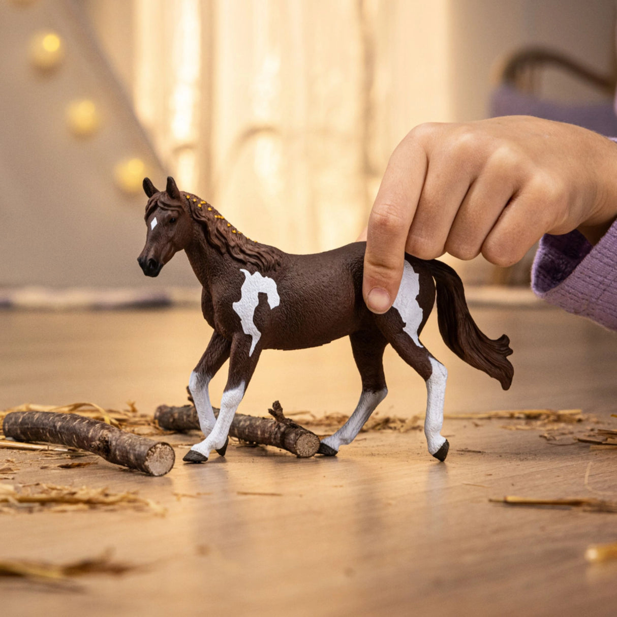 A child playing with a Schleich horse toy Paint Horse Mare inside a playroom