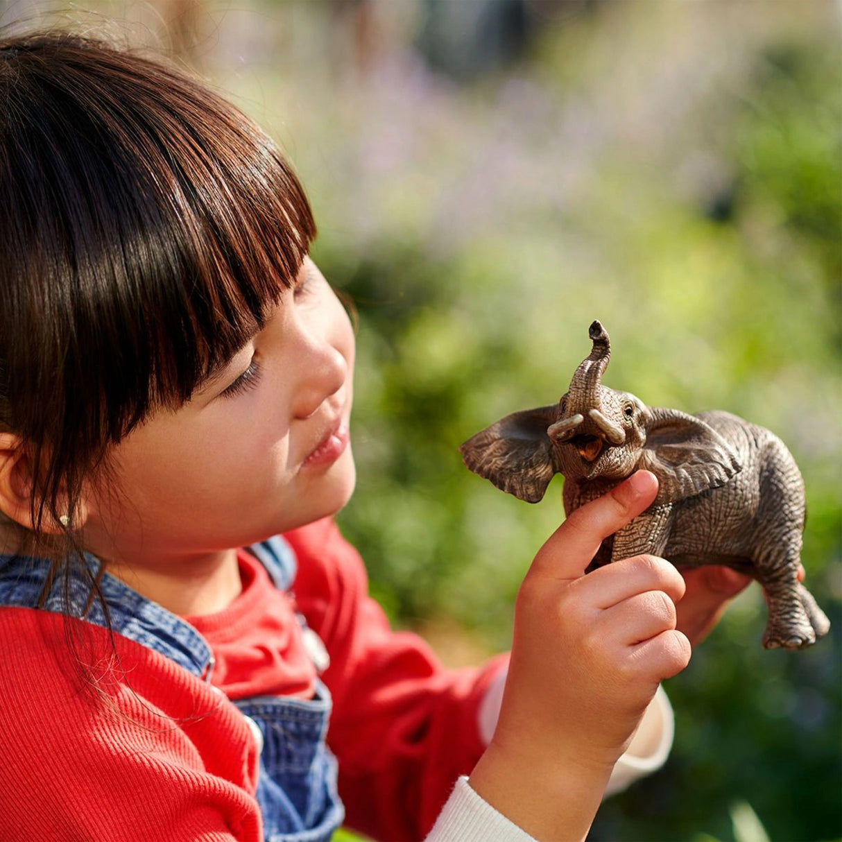 Child playing with Schleich African Elephant wild animal toy in a playground