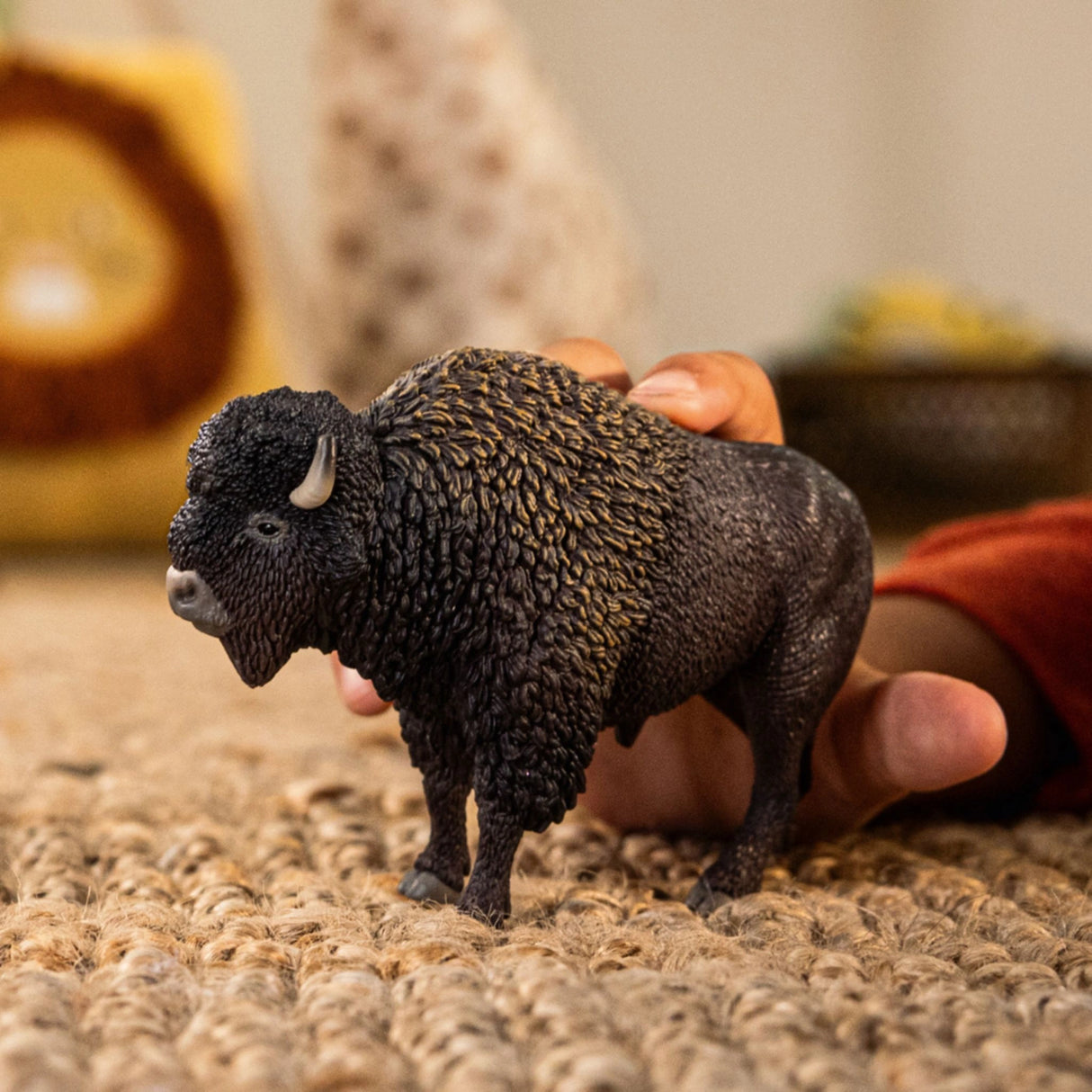 A child playing with a Schleich bison wild animal toy in a playroom