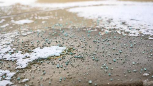 ice-melting salt is spread over a walkway with some snow and ice still visible