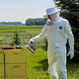 A beekeeper in a bee suit using a smoker to harvest honey in Kamloops, British Colombia
