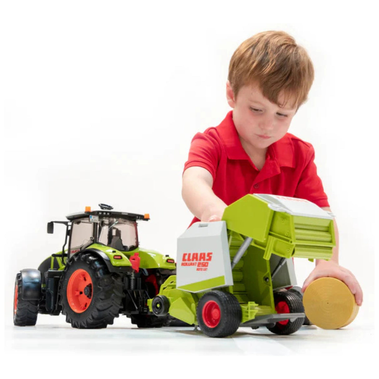 A child playing indoors with the Bruder Claas Rollant 250 Straw Baler farm toy