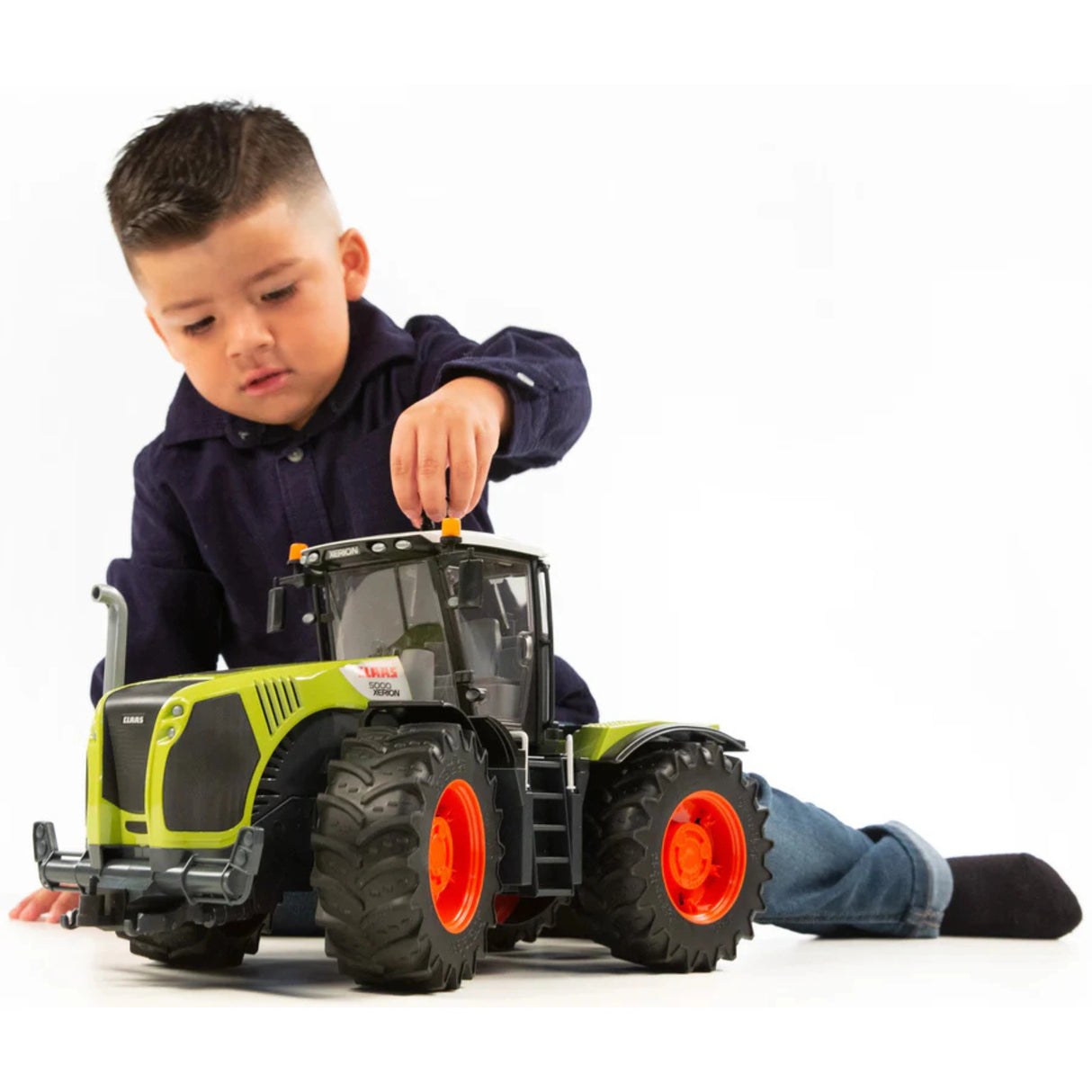 Child playing indoors with Bruder Claas Xerion tractor toy