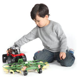 A Bruder Krone Dual Rotary Swath Windrower farm toy being played with by a kid indoors