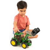 Child playing with Bruder John Deere Toy tractor with front loader