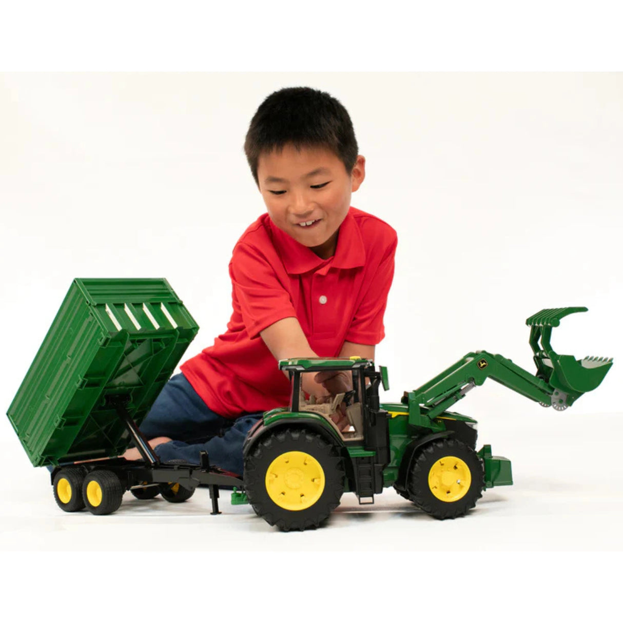 Child playing with Bruder 7R Tractor with Front Loader and Trailer John Deere Toy