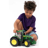 Child playing with Bruder 7R 350 Tractor John Deere Toy