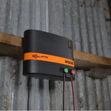 A Gallagher M1500 Mains Fence Energizer installed on a wooden plank, inside a barn in Kamloops, British Colombia