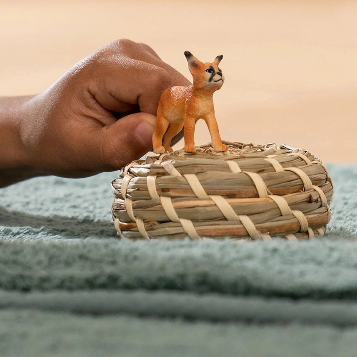 A young child playing with Schleich Caracal Baby Wild Animal Toy indoors