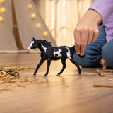 A child playing with the Schleich Paint Horse Gelding toy horse indoors